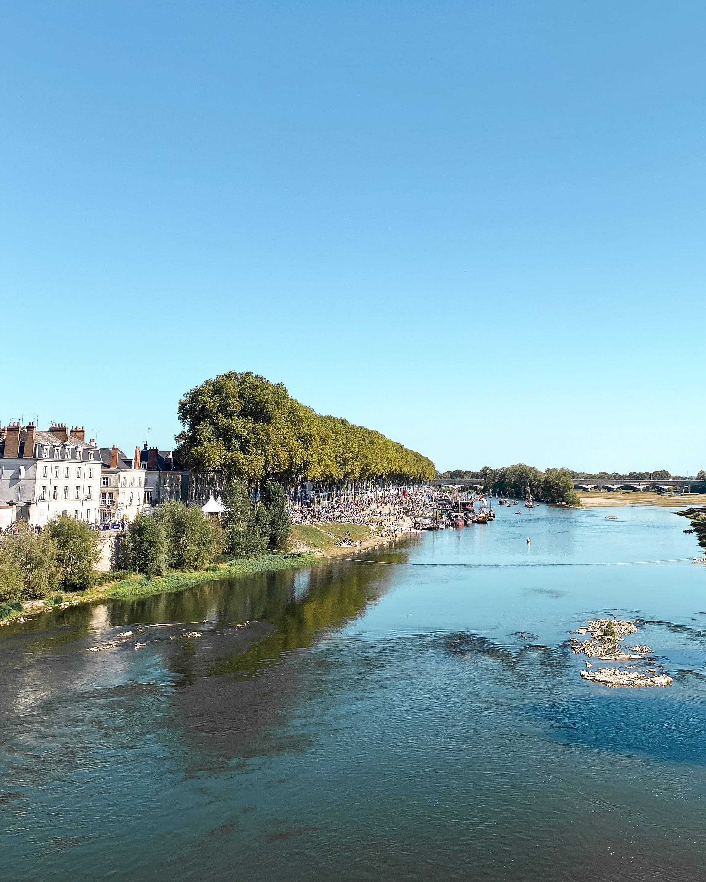 La Loire vue d'un pont ; à gauche les quais et des immeubles ; on aperçoit des bateaux au fond
