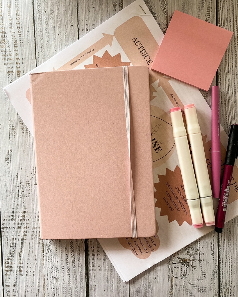 Un carnet rose ; des stylos et papiers roses